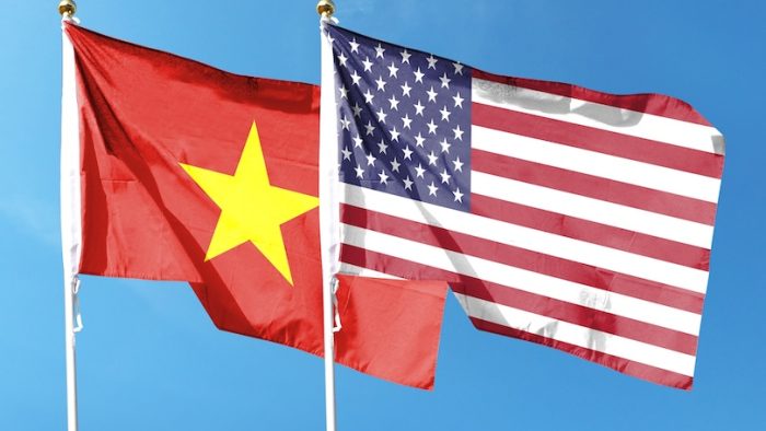 American flag and Vietnam flag on cloudy sky. fluttering in the sky