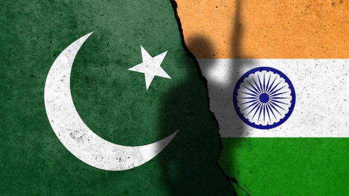 Flags of Pakistan and India painted on the concrete wall with soldier shadow. Kashmir crisis