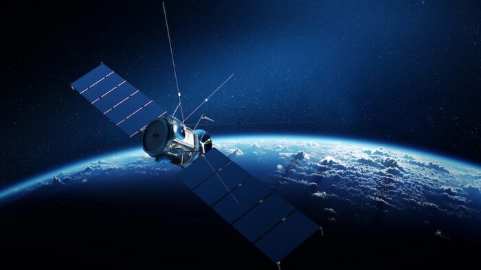 Communications satellite orbiting Earth with sunrise in space