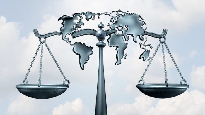 International law and global legal system concept as a justice scale shaped as the world as a metaphor for diplomatic treaty agreement or relations among nations as a 3D illustration.