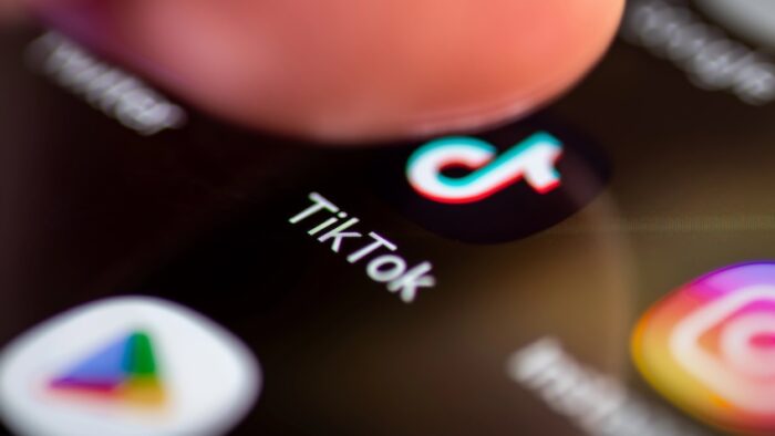 London. UK- 12.31.2022. A person pressing on the symbol, icon of the social media application Tik Tok on the screen of a smartphone.