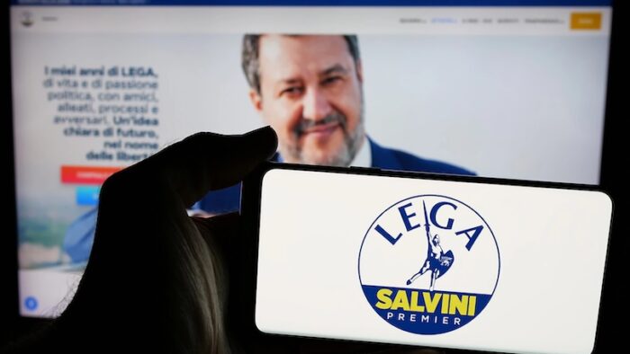 Stuttgart, Germany - 07-17-2025: Person holding mobile phone with logo of Italian party Lega per Salvini Premier (LSP) on screen in front of web page. Focus on phone display.